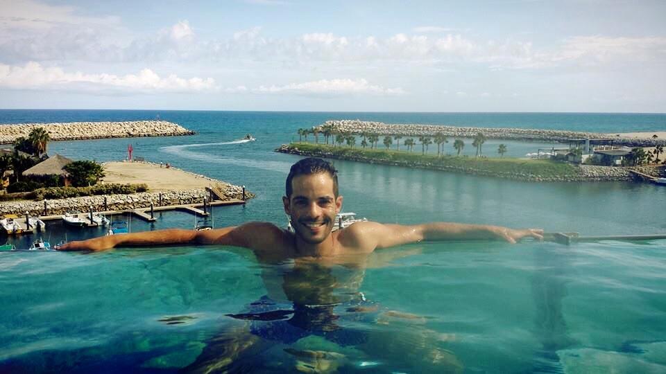 Daniel in an infinity pool overlooking a luxury marina